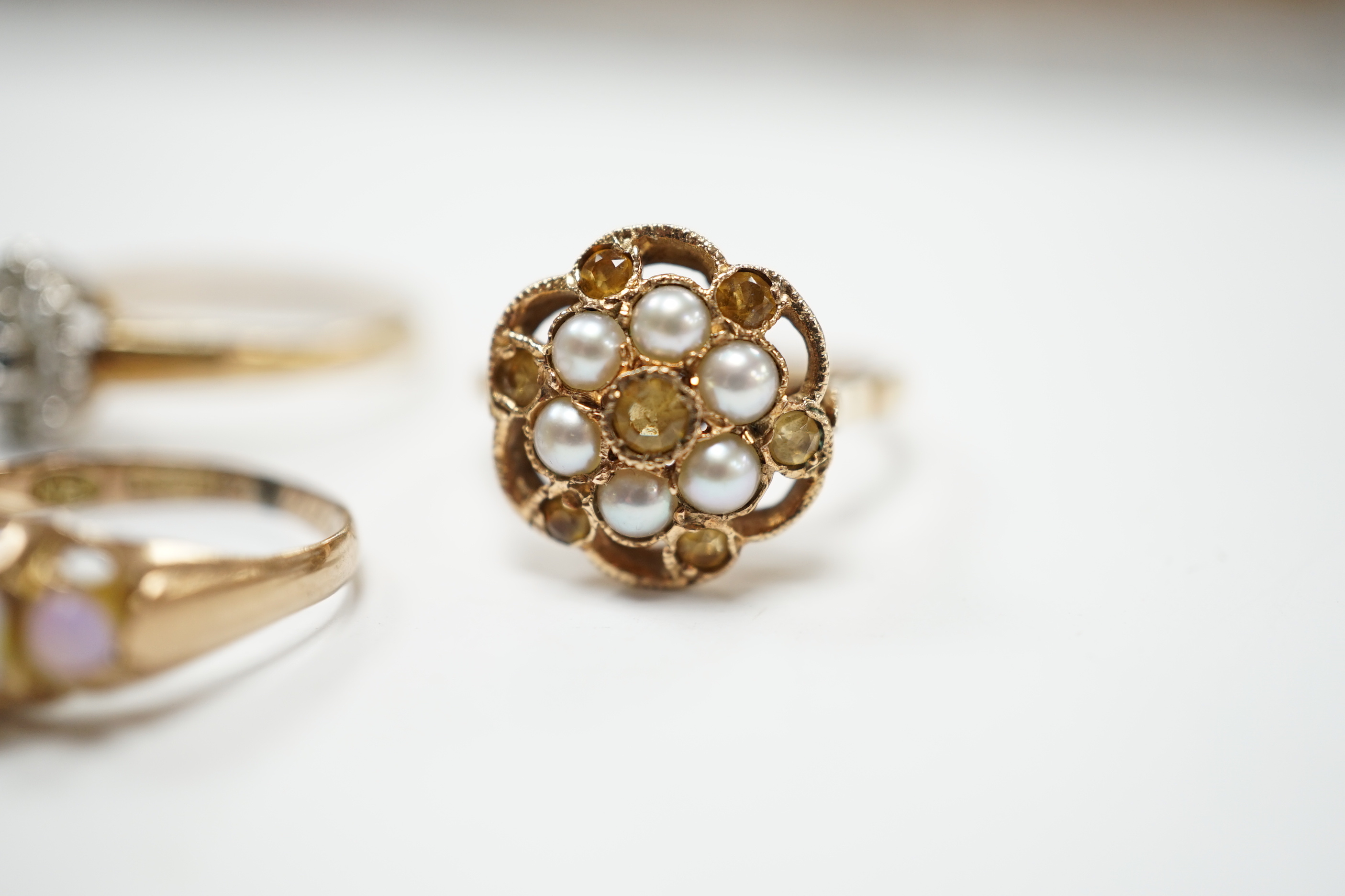 A late Victorian 9ct gold and graduated five stone opal set half hoop ring, size L, a 9ct, seed pearl and citrine cluster set flower head ring, gross 4.7 grams and a costume ring.